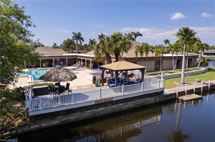 Back of property with a gazebo, a deck with water view, a community pool, and a patio area