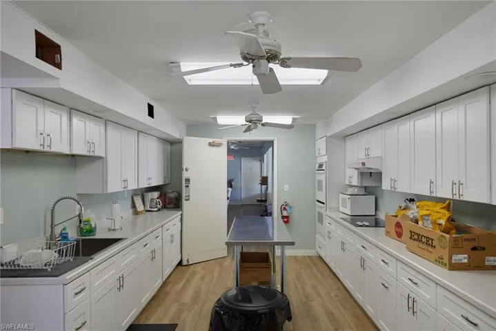 Kitchen featuring white cabinets, light wood finished floors, ceiling fan, and white appliances