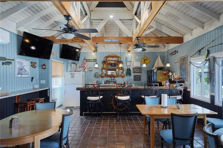Dining area with wood ceiling, ceiling fan, wood walls, a wall mounted AC, and dark tile patterned flooring