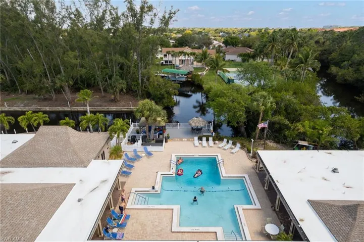 Community pool with view of scattered trees, a patio area, and a water view