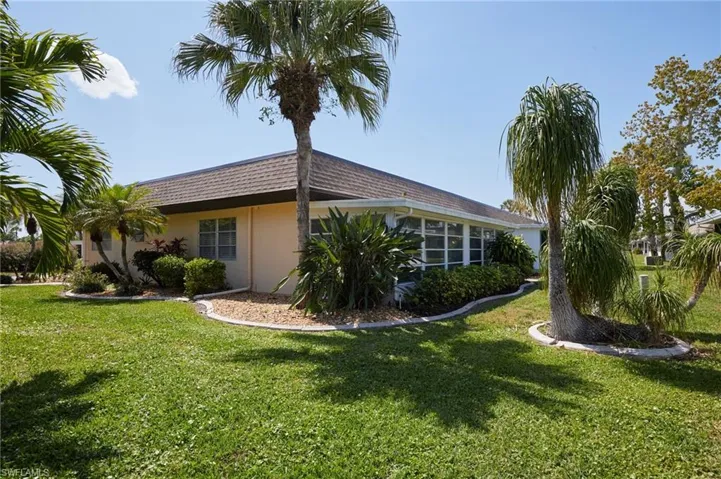 View of side of property with stucco siding, a lawn, and a sunroom