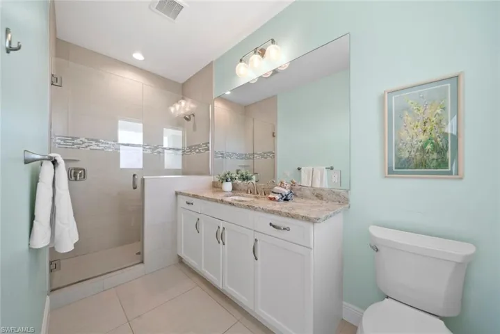 Bathroom featuring tile patterned floors, vanity, a shower with shower door, and toilet