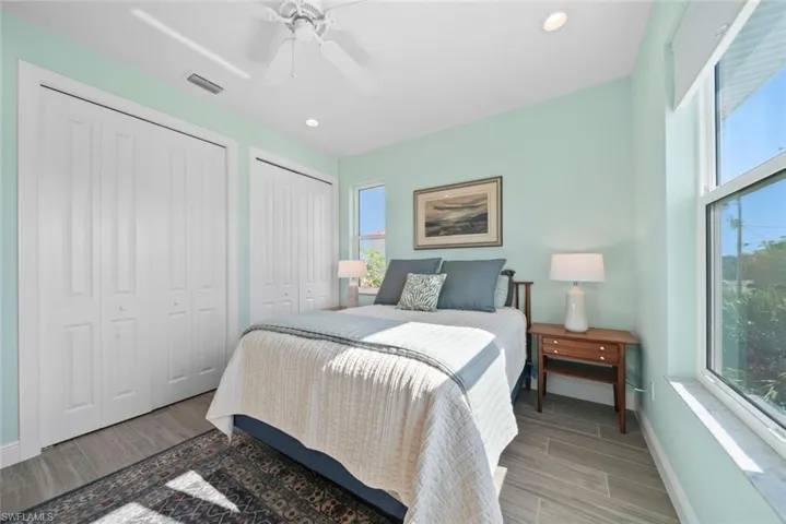 Bedroom with multiple windows, two closets, light hardwood / wood-style flooring, and ceiling fan
