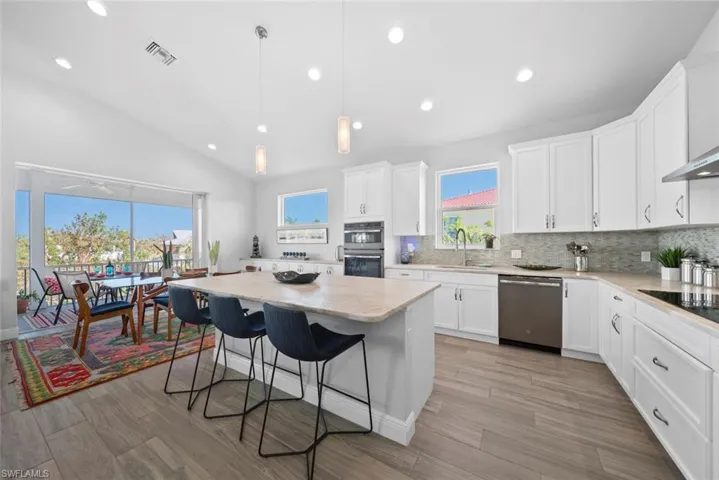 Kitchen with sink, stainless steel appliances, a wealth of natural light, and vaulted ceiling