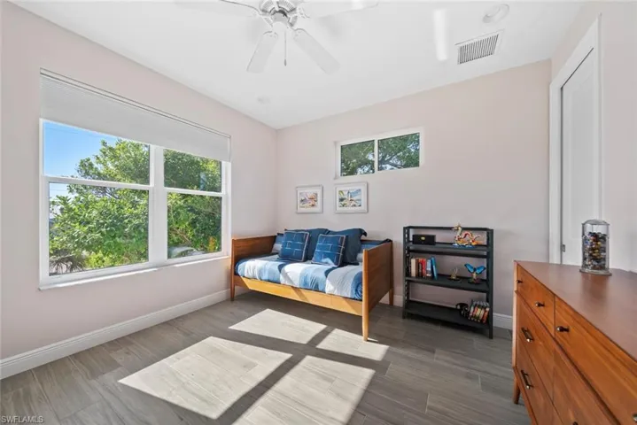 Bedroom with multiple windows, ceiling fan, and dark wood-type flooring