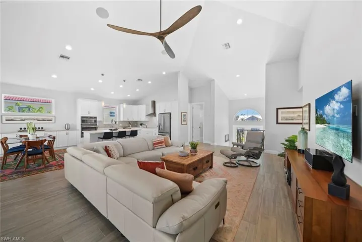 Living room featuring light wood-type flooring, high vaulted ceiling, and ceiling fan