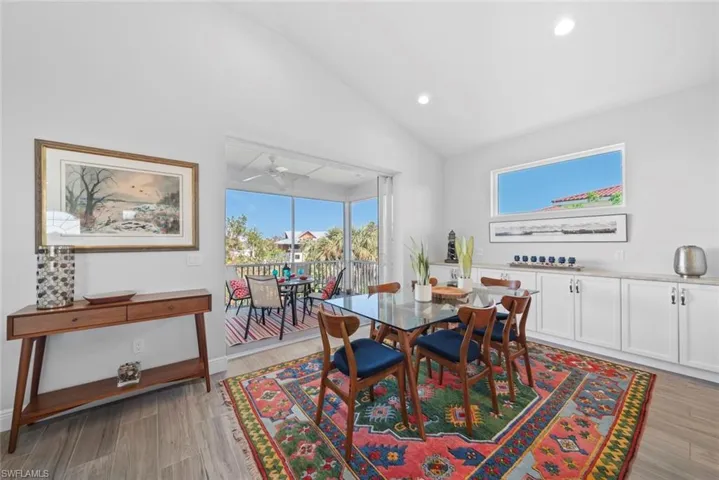 Dining room with ceiling fan, light wood-type flooring, and vaulted ceiling