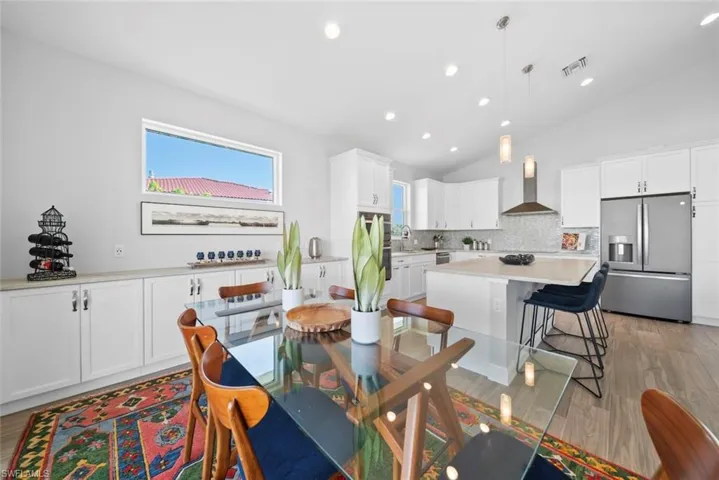 Dining area with light hardwood / wood-style floors, vaulted ceiling, and sink
