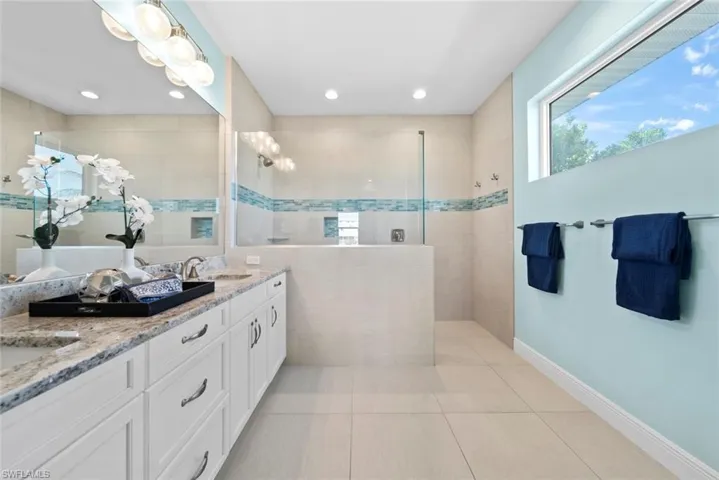 Bathroom with a tile shower, tile patterned flooring, and vanity