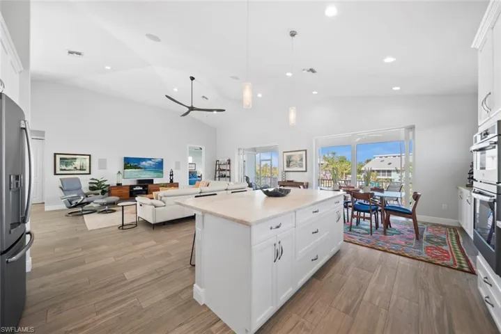 Kitchen featuring stainless steel appliances, ceiling fan, a center island, light hardwood / wood-style floors, and white cabinetry