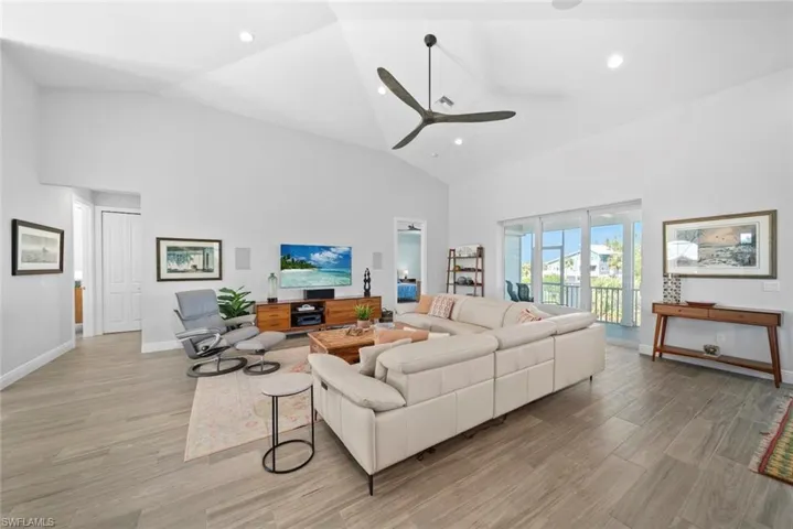 Living room featuring ceiling fan, light hardwood / wood-style flooring, and high vaulted ceiling