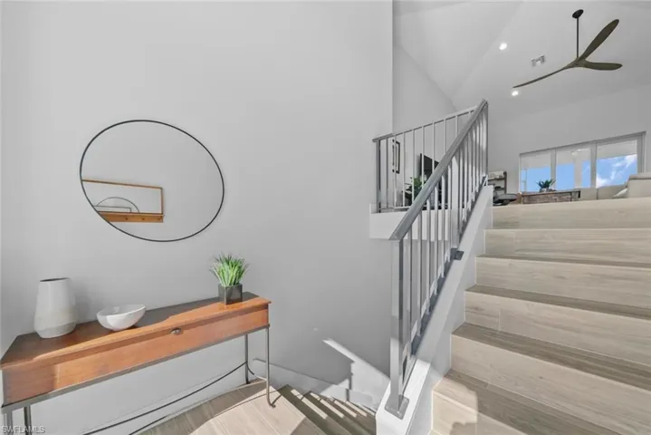 Stairway with hardwood / wood-style floors, ceiling fan, and lofted ceiling