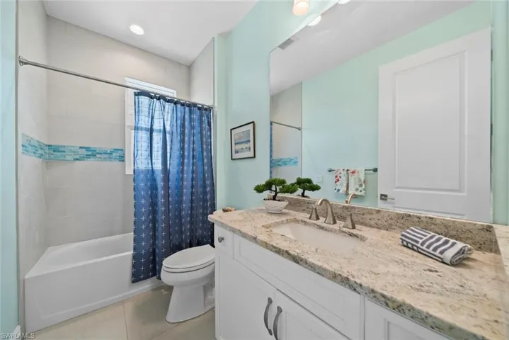 Full bathroom featuring tile patterned floors, shower / bath combo, toilet, and vanity