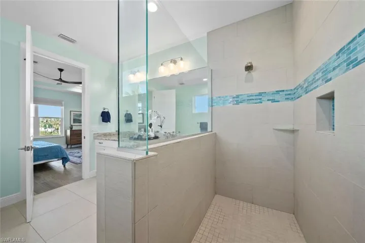 Bathroom featuring tile patterned flooring, a tile shower, and ceiling fan
