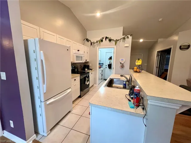 Kitchen with breakfast bar, newer refrigerator and entry to indoor laundry room.