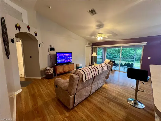 Living room featuring ceiling fan, wood-type flooring, and cathedral ceiling
