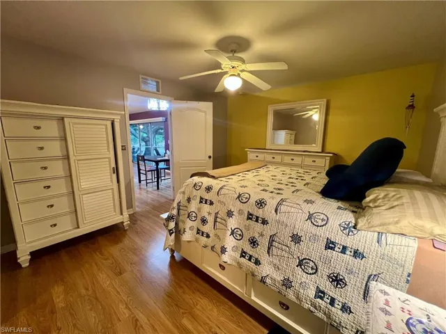 Primary bedroom with ceiling fan and hardwood / wood-style floors