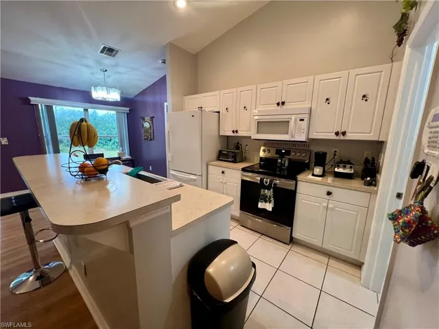 Kitchen with decorative light fixtures, white cabinets, and a center island