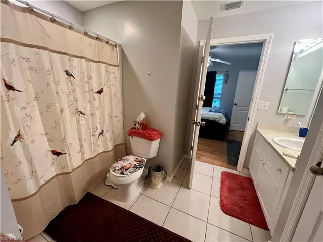 Bathroom featuring toilet, tile patterned floors, vanity, and curtained shower
