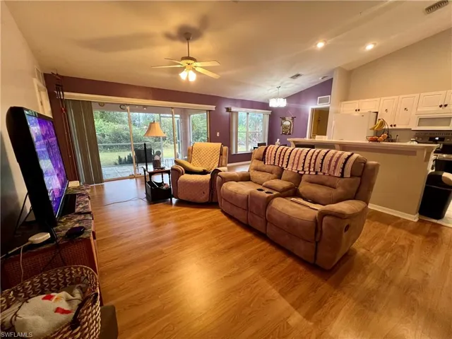 Living room with cathedral ceiling, ceiling fan, a wealth of natural light, and light wood-type flooring
