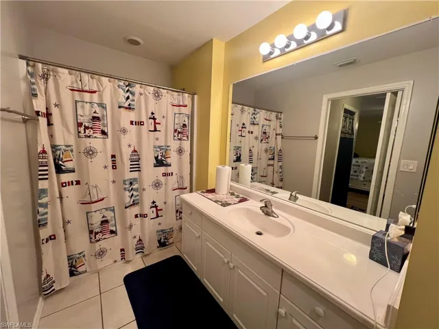 Primary bathroom featuring walk in shower, tile patterned floors, and vanity