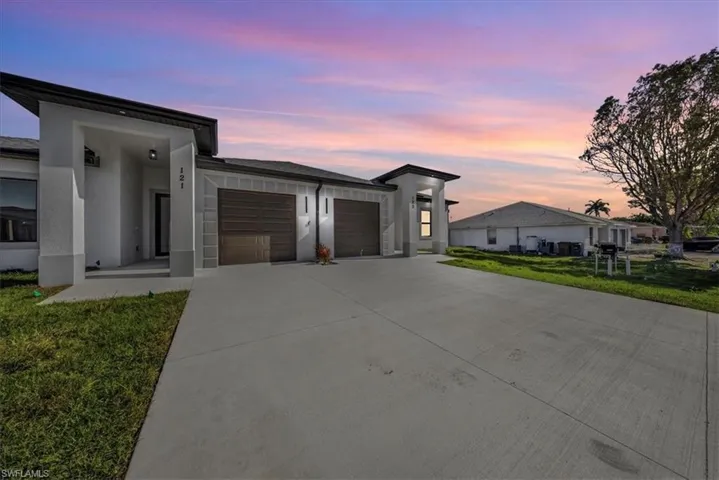 Modern home featuring a lawn, driveway, an attached garage, and stucco siding