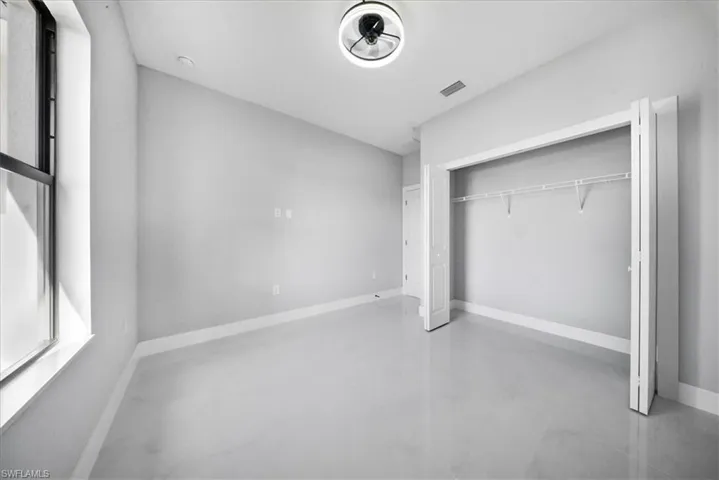 Unfurnished bedroom with concrete floors and a closet