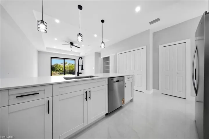 Kitchen with white cabinets, decorative light fixtures, stainless steel appliances, recessed lighting, and open floor plan