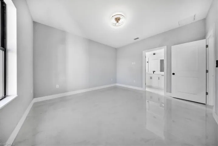 Unfurnished room featuring finished concrete flooring and baseboards