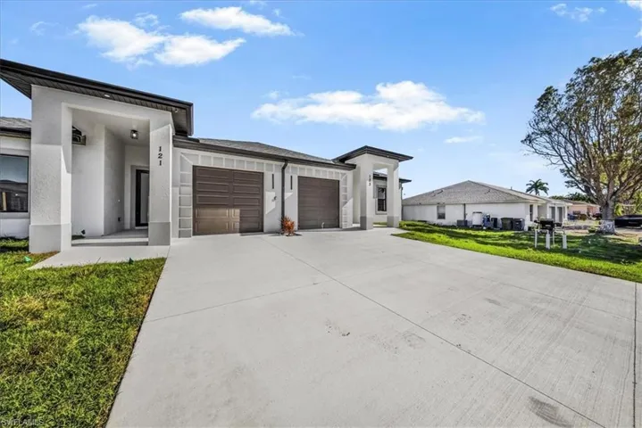 View of front facade with a front yard, stucco siding, driveway, and a garage
