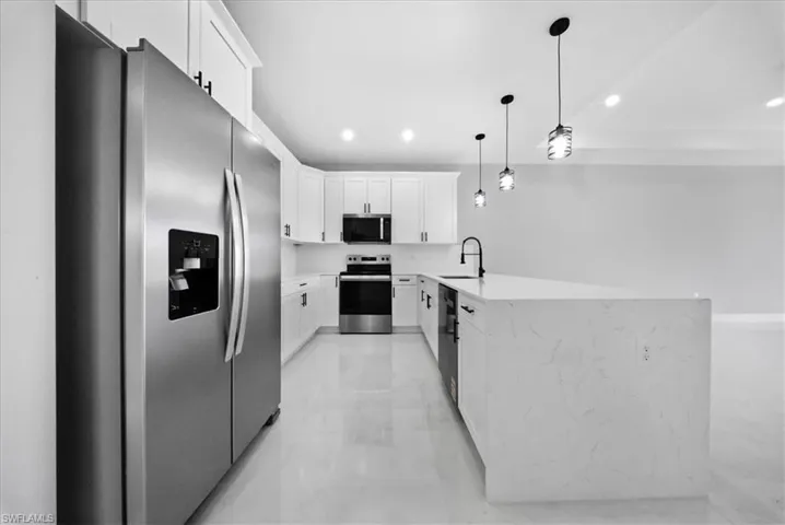 Kitchen featuring black appliances, white cabinetry, a peninsula, light stone countertops, and recessed lighting