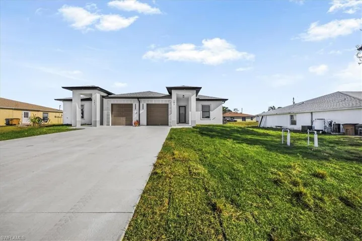 Prairie-style home featuring a front lawn, driveway, stucco siding, and a garage