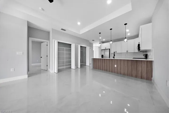 Kitchen featuring white cabinets, open floor plan, stainless steel refrigerator with ice dispenser, decorative light fixtures, and a peninsula