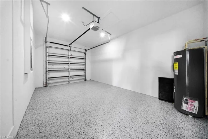 Garage featuring electric water heater and a garage door opener