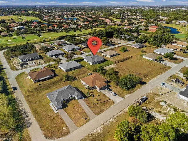 Aerial view of property and surrounding area with a nearby body of water, a local golf course, and nearby suburban area