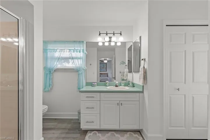 Bathroom featuring a white vanity with a light green countertop, an integrated sink, and brushed nickel hardware