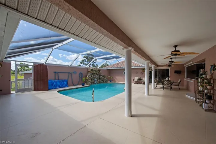 Screened lanai featuring a free-form pool with a rock waterfall