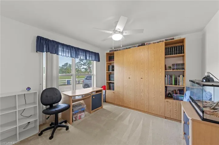 Room featuring a large window, comprehensive built-in cabinetry, integrated shelving, and carpeted flooring