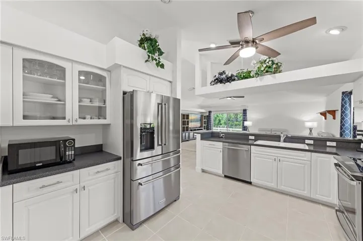 Kitchen featuring white cabinetry, dark countertops, stainless steel appliances, and tile flooring