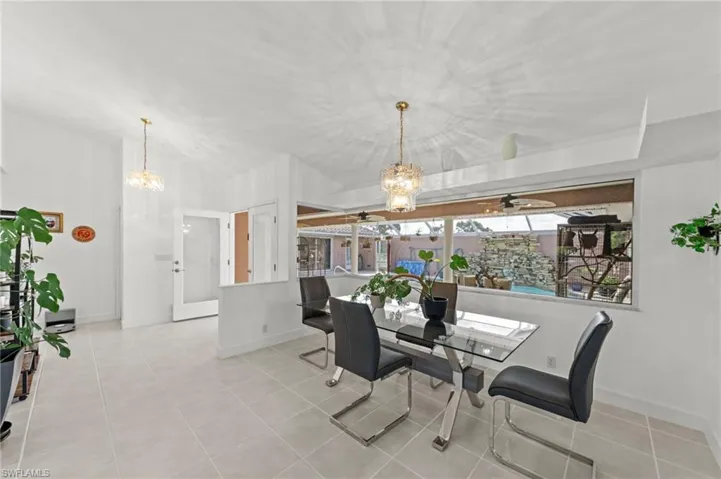 Dining area featuring vaulted ceilings, a contemporary chandelier, and light-toned tile flooring
