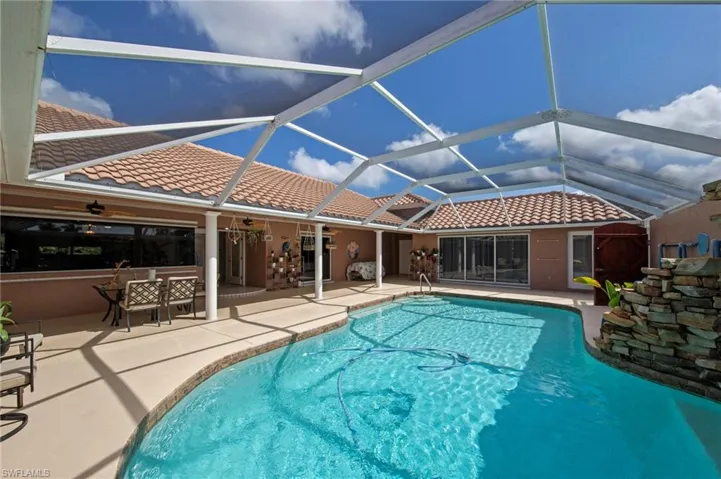 Screened enclosure over a curvilinear swimming pool with concrete decking