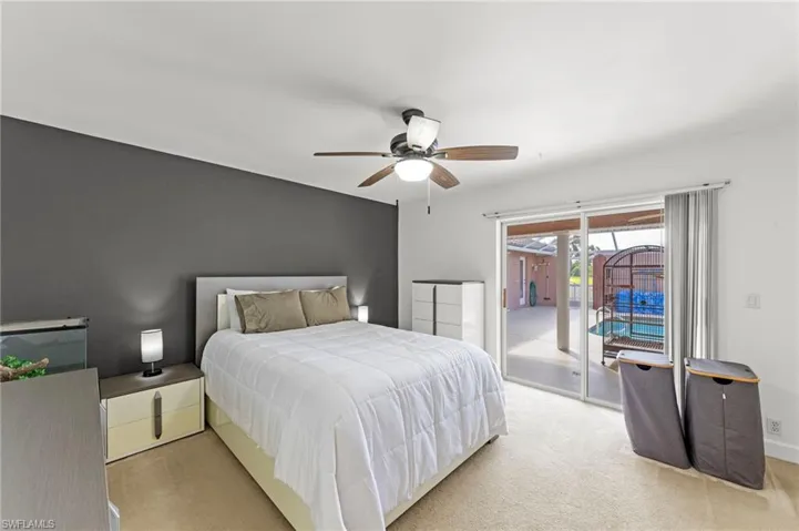 Carpeted interior space featuring a dark accent wall, ceiling fan with light fixture, and sliding glass doors