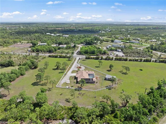 Expansive acreage featuring a single-story residence with a tile roof, an integrated pool, and a screened enclosure