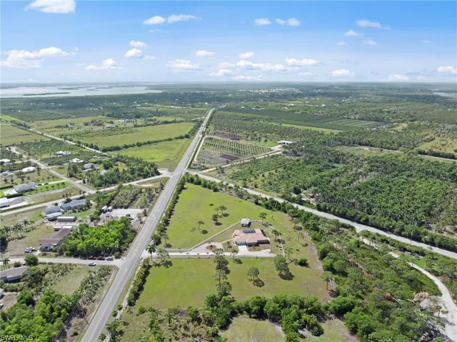 Expansive agricultural landscape featuring a single-story residence with a red tile roof, surrounded by mature trees and open green spaces