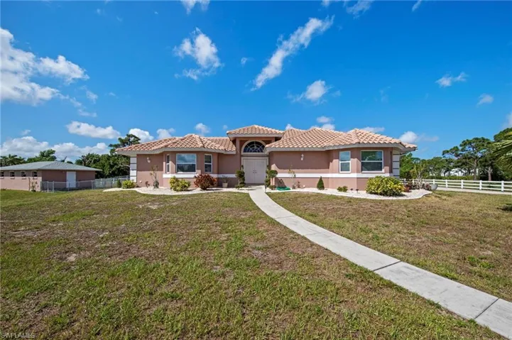 Stucco exterior residence featuring a tile roof, arched entryway, and multiple front windows
