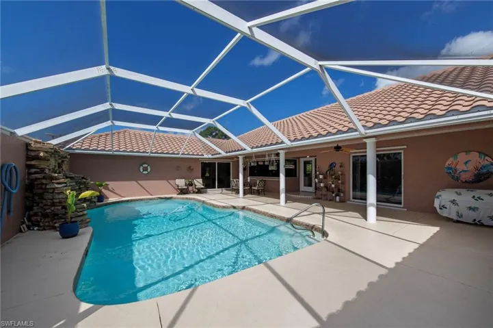 Screened swimming pool enclosure featuring a rock-stacked water feature and a tiled roofline