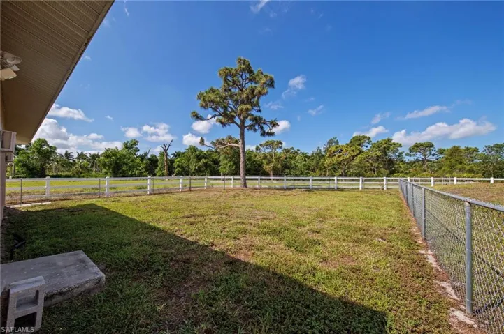 Expansive grassy yard area with a chain-link fence