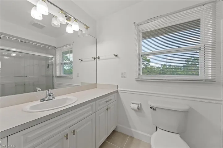 Bathroom featuring a wide vanity with an integrated sink, polished chrome faucet, and white cabinetry