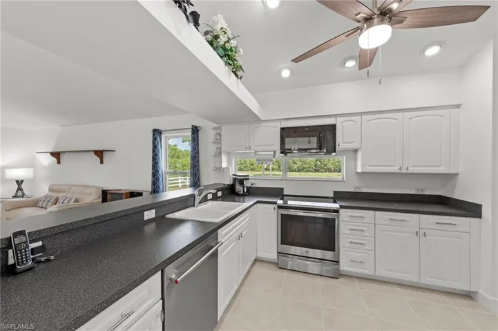Kitchen featuring white cabinetry, dark countertops, stainless steel appliances, recessed lighting, and a ceiling fan