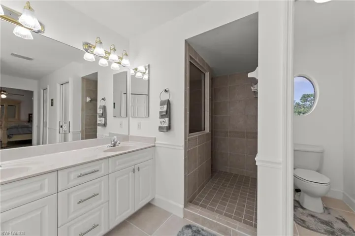 Bathroom featuring a dual vanity with white cabinetry, light-toned countertop, and a full-width mirror